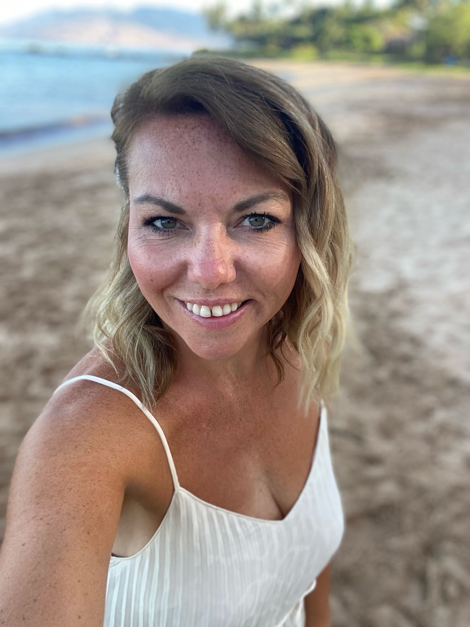 A person in a white top poses playfully on a beach, appearing in several shots with a joyful smile.