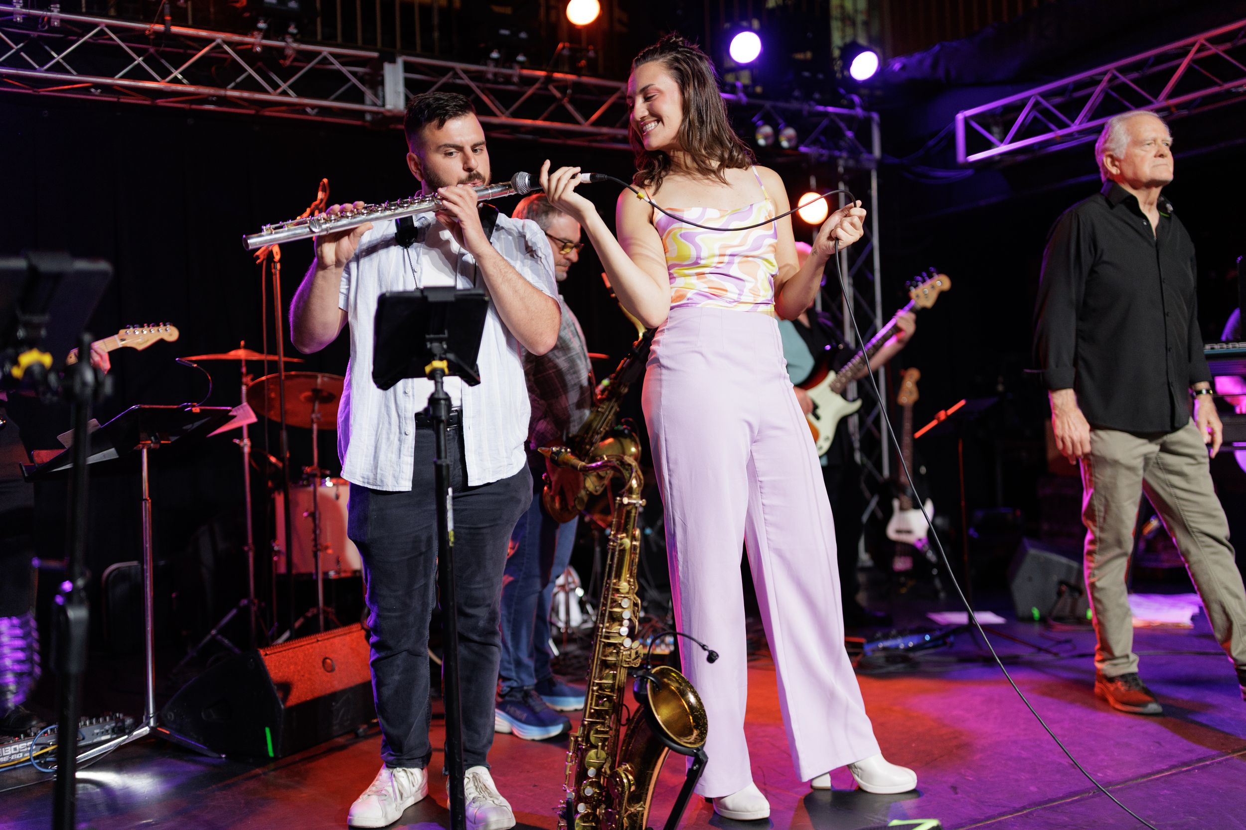Musicians perform on stage with colorful lighting during a concert performance.