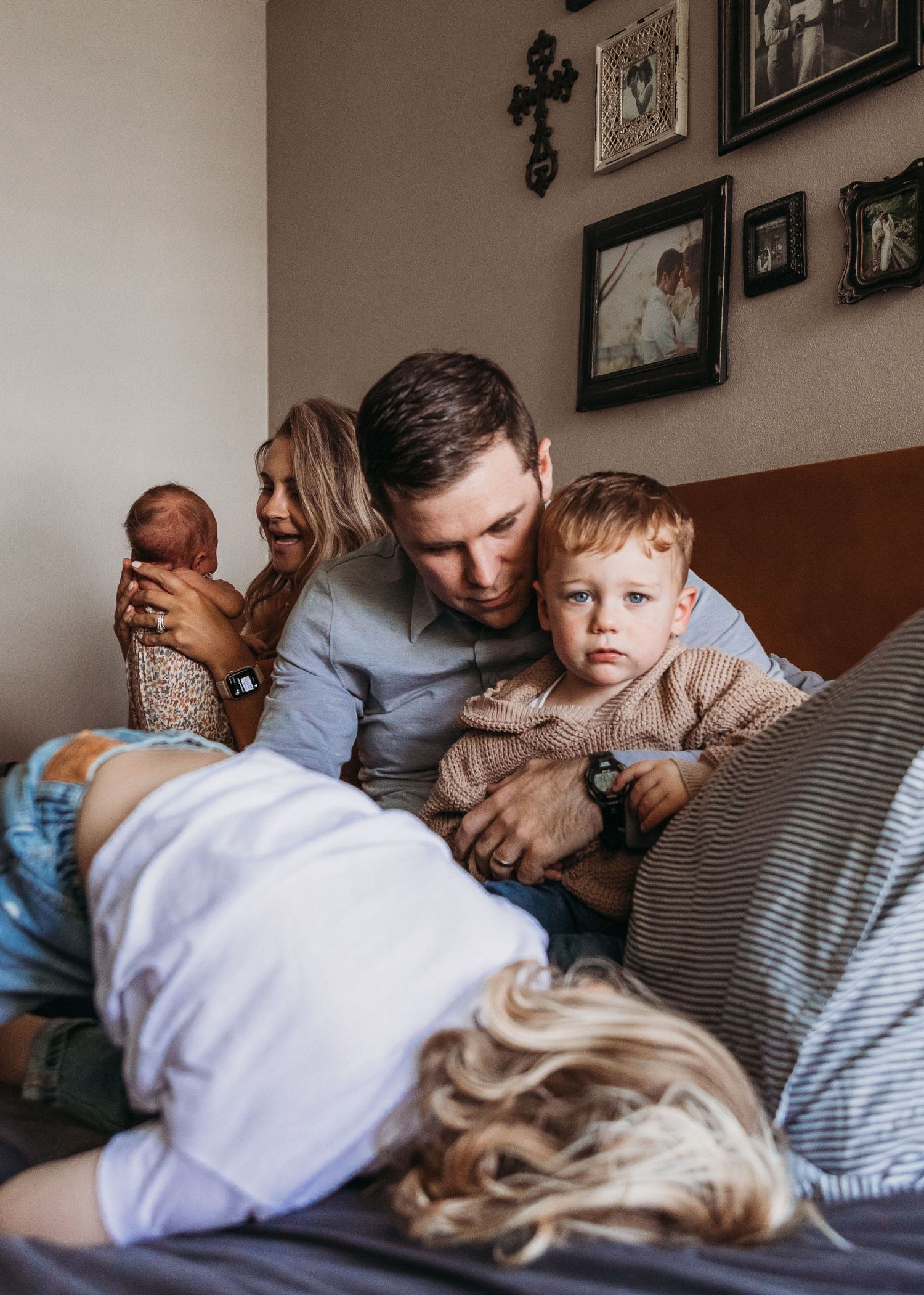 A cozy family moment on the bed as they snuggle together with a baby in warm, intimate lighting.