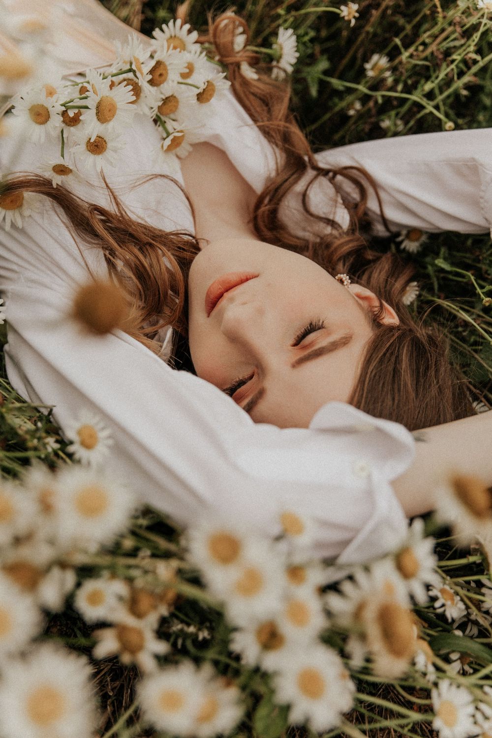 Dreamy portrait among blooming daisies in soft natural lighting.