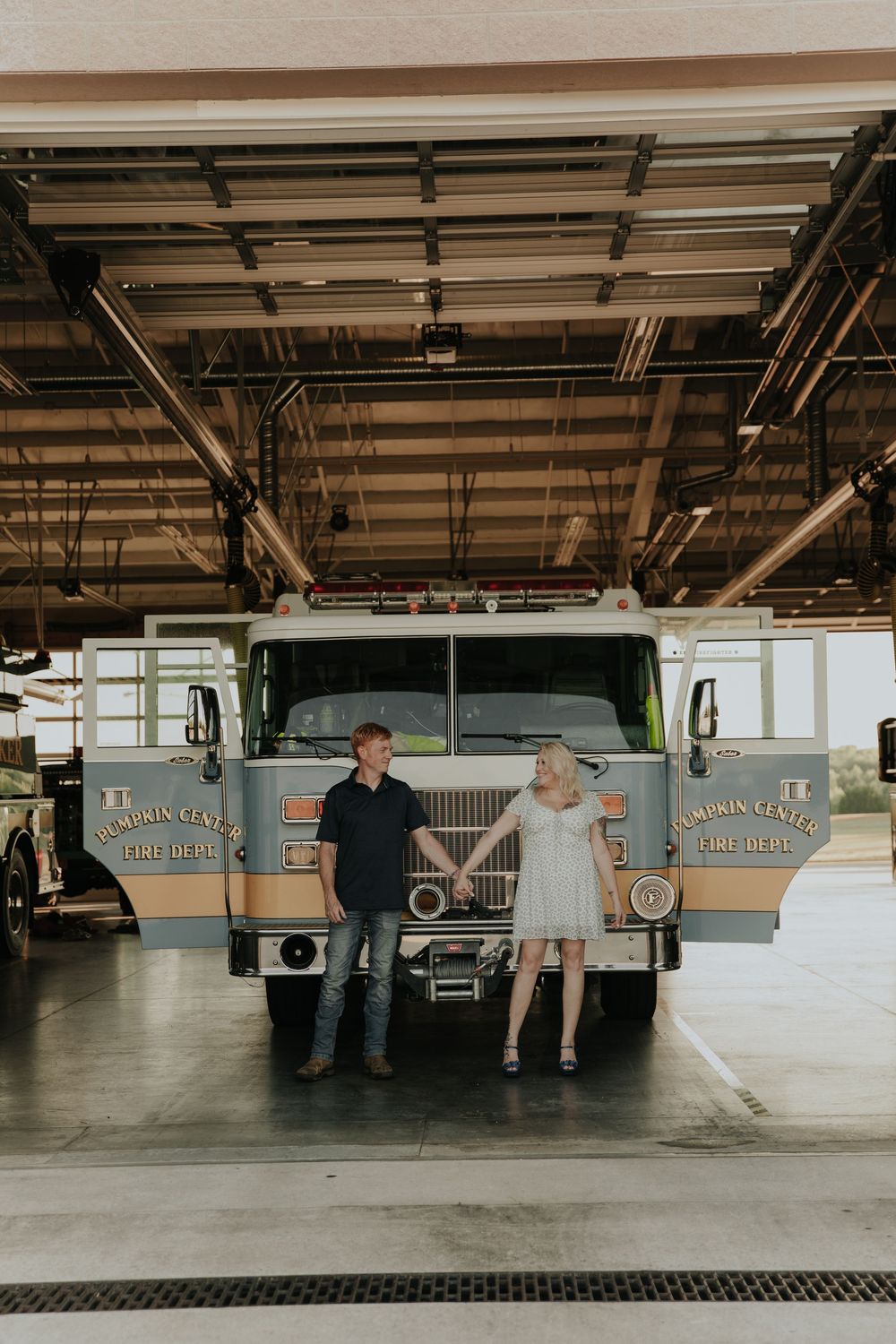 Wedding party gathered around vintage trucks in an industrial garage setting.