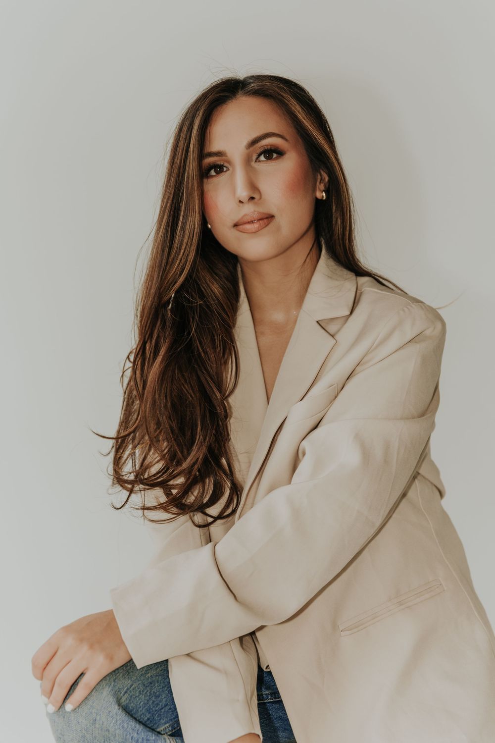 Fashion portrait series in beige blazer against minimal white studio background.