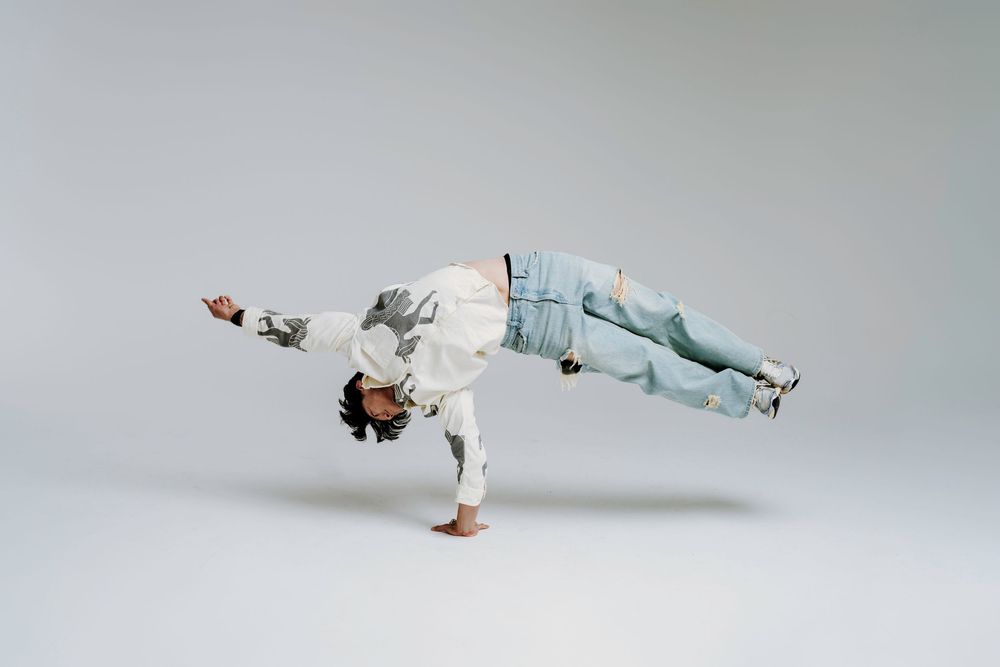 Dancer in white attire performs a graceful falling sequence across multiple dynamic poses against a light studio background.