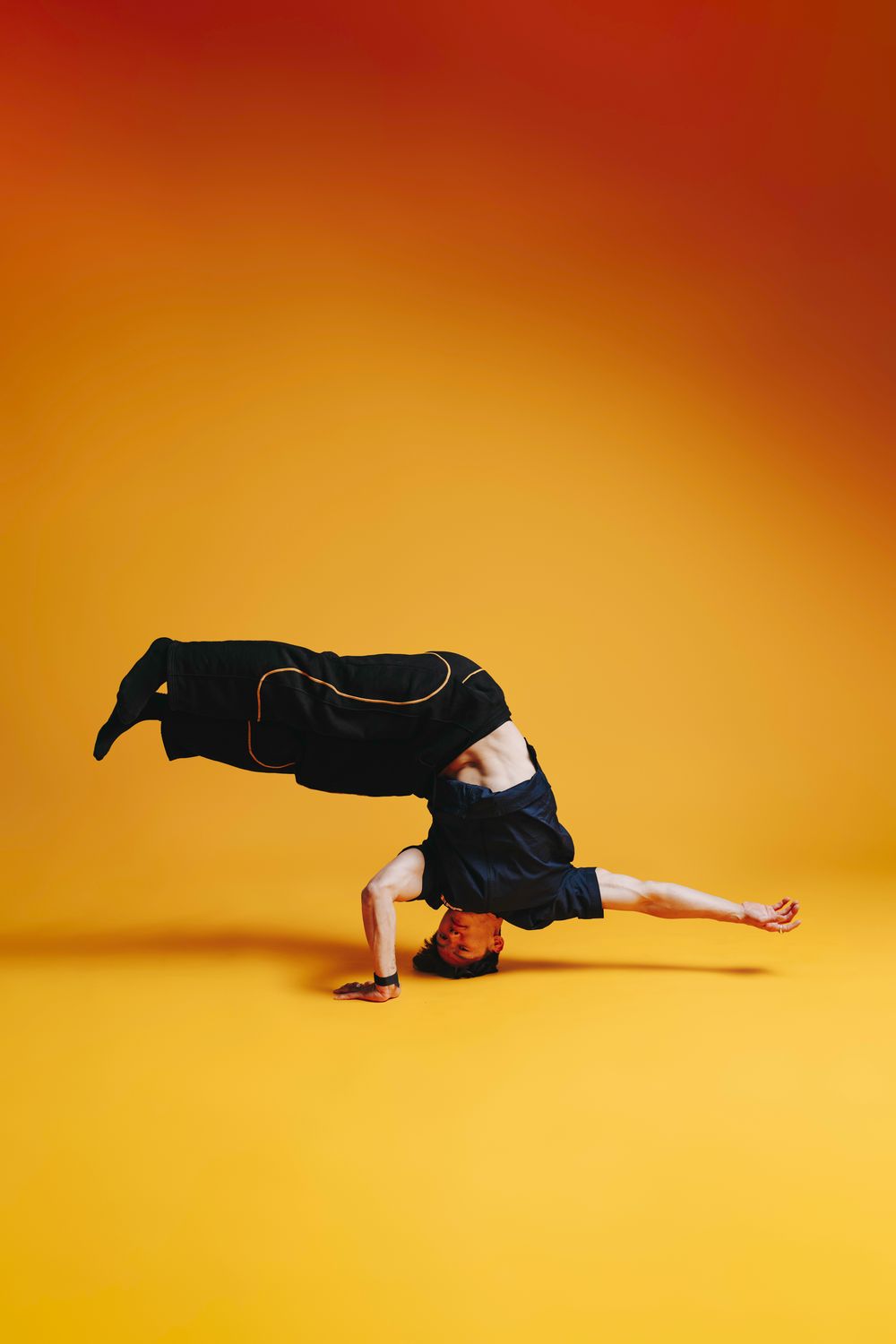 Woman performing break dancing movement sequence against vibrant yellow background with dramatic gradient lighting.