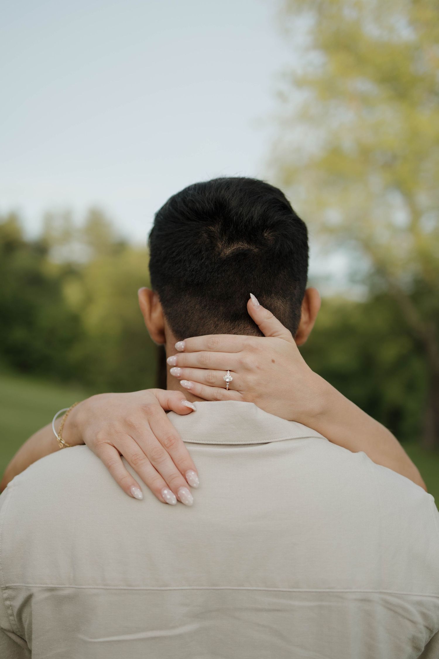A sequence of photos showing proposal moments on a grassy lawn with trees and a stone building in the background.