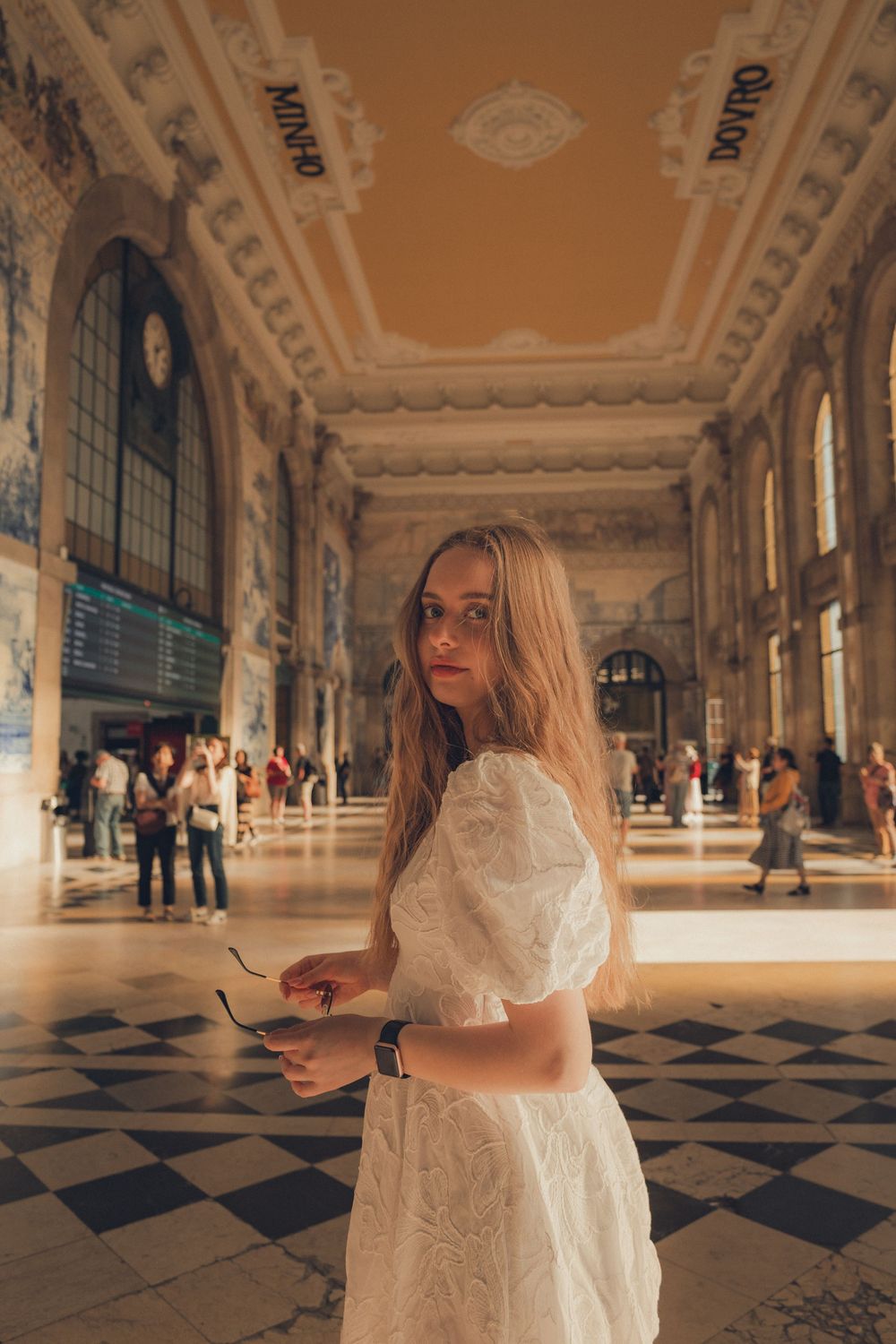 Elegant scene in historic hall with checkered floor and ornate ceiling.