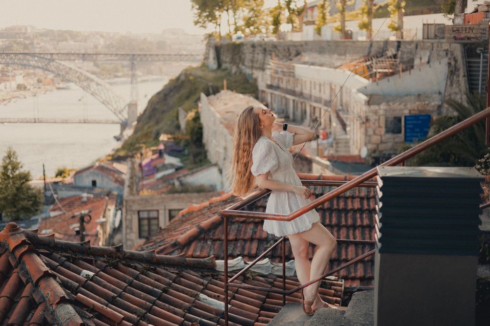 White summer dress against backdrop of Porto's iconic rooftops and bridge at sunset.