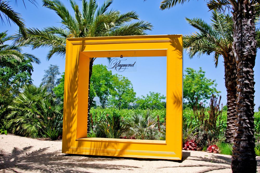 A bright yellow archway frames an ocean view with tropical palm trees and blue skies.