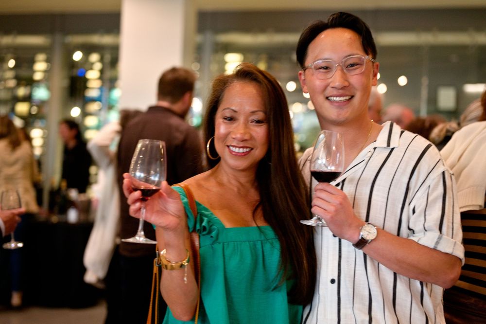 A couple enjoying wine together at a social gathering in a restaurant with bright lighting and festive atmosphere.