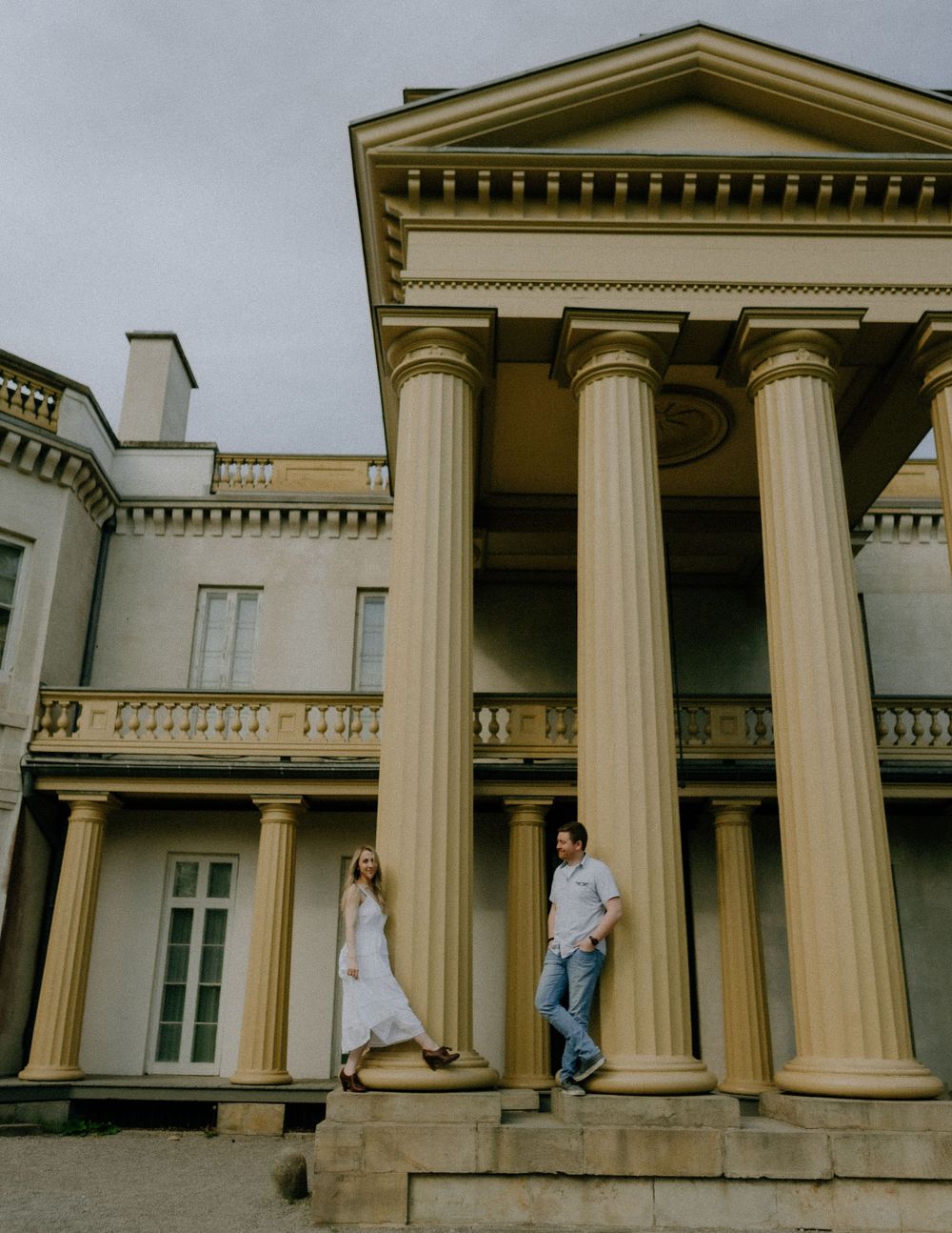 A collage of people sitting and posing on the white pillars and steps of a neoclassical building exterior.