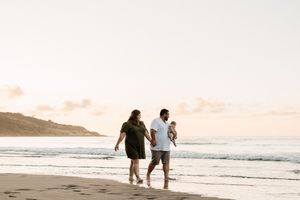 Silhouettes of people walking along a beach shoreline during golden hour.