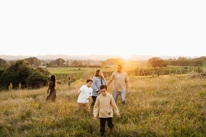 Family walking together in a golden meadow during sunset.