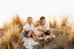 A family shares tender moments together in a sunlit field of tall golden grass.