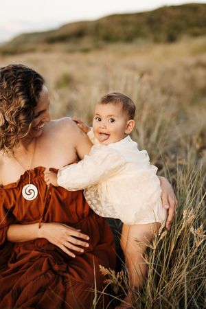 A tender moment captured between parent and baby in tall grass during golden hour.