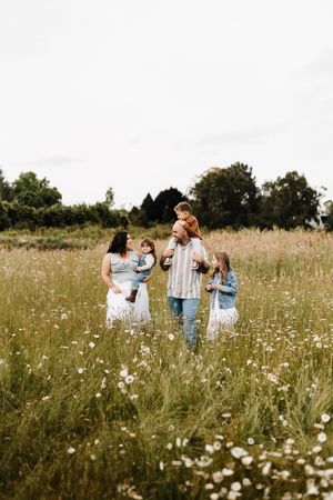 People gathered in field of white wildflowers on summer afternoon.