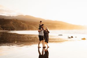 Couple enjoying a romantic moment on a beach at sunset with reflections in the wet sand.