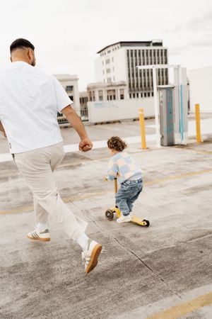 Adult and child playing together on urban rooftop parking area.