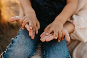 Close-up view of a child and mother's hands together