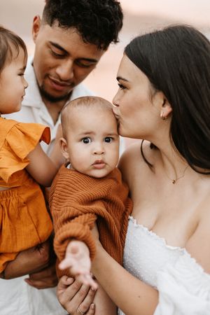 Close-up portrait of young family with two children showing affection outdoors.