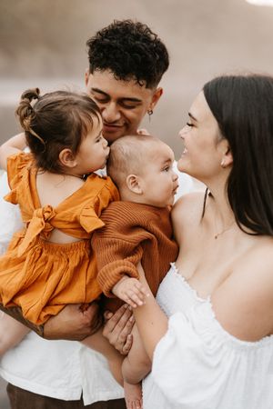 An intimate close-up series showing a family's tender moments together in white and orange clothing.