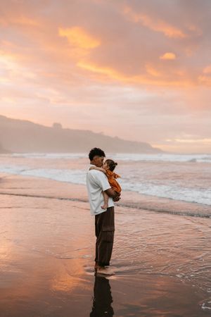 Beautiful sunset beach scene with silhouettes against orange sky and crashing waves.