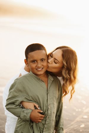 Tender moment between mother and son against warm sunset backdrop.
