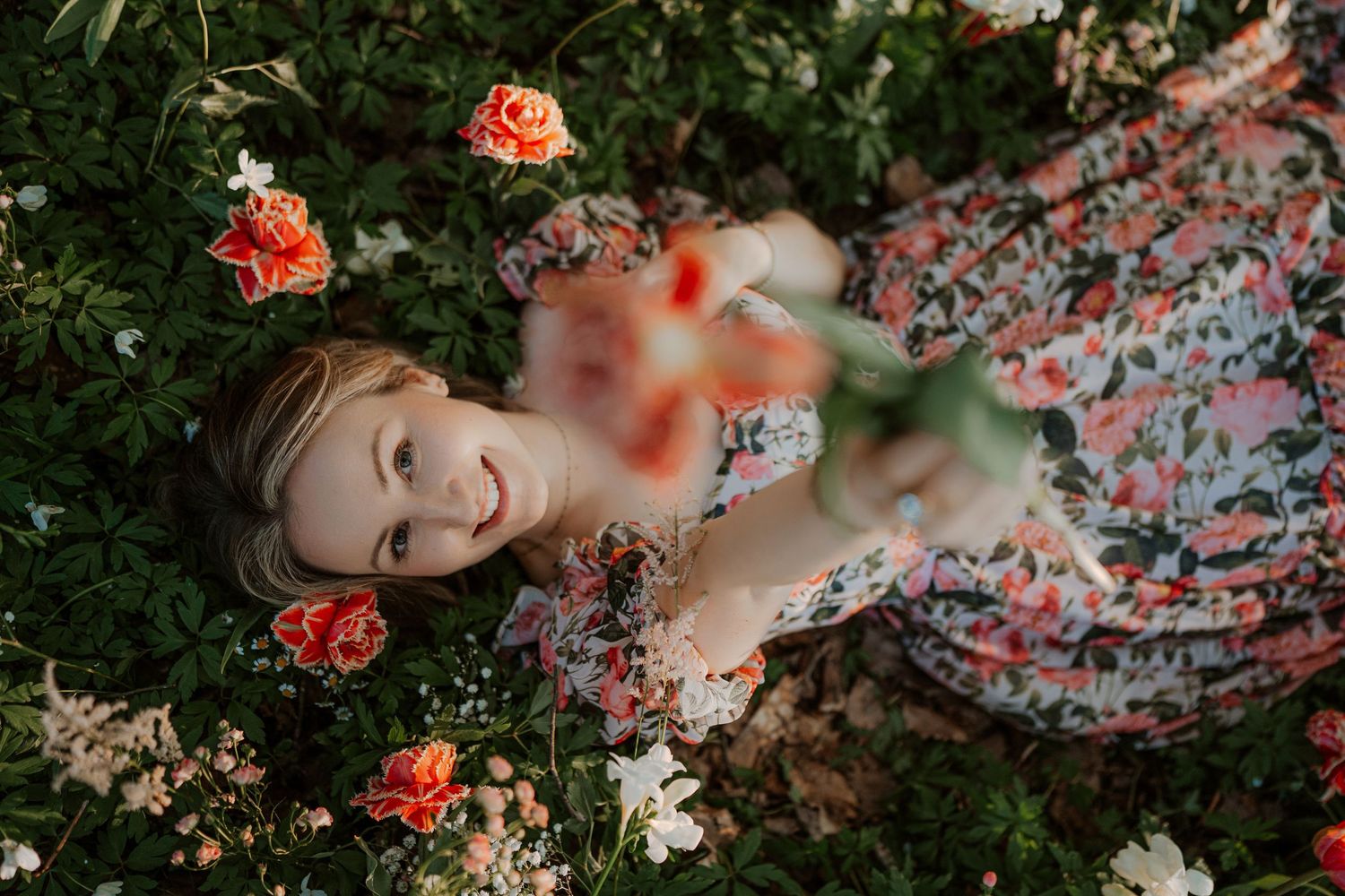 A serene figure lies among vibrant orange flowers and lush greenery in a dreamy outdoor garden setting.