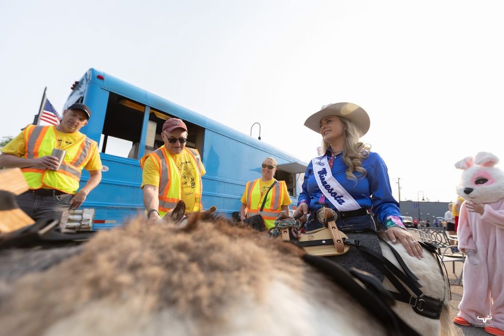 People in western attire and yellow shirts gather around donkeys near a blue bus. Pro Rodeo PRCA Rodeo Photographer Dakota Cardenas