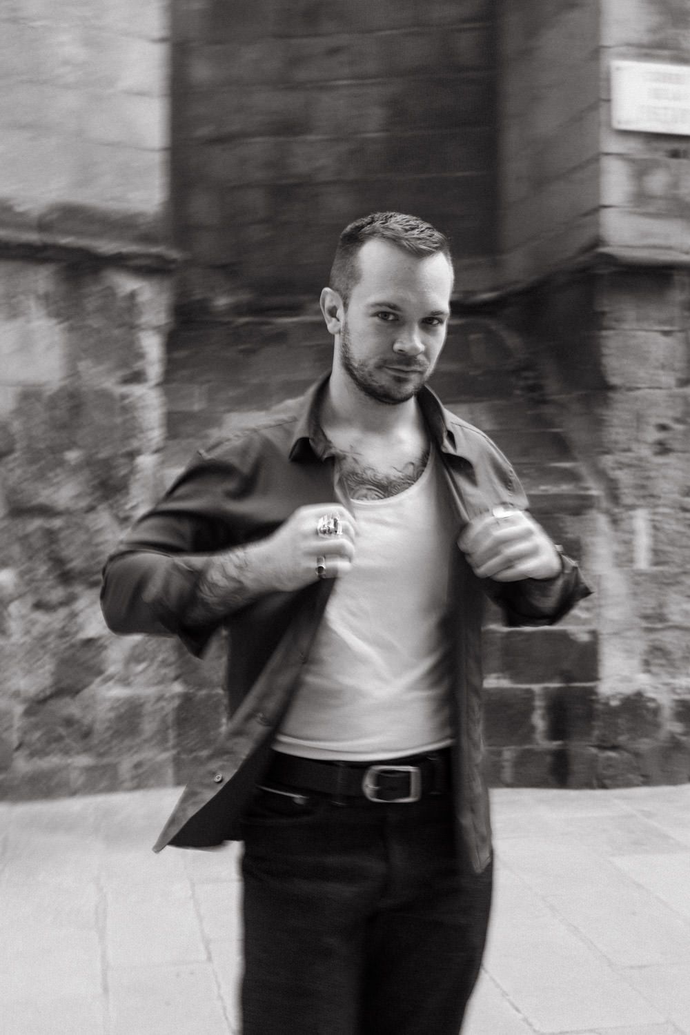 Artistic black and white sequence of person in leather jacket moving through stone corridor.