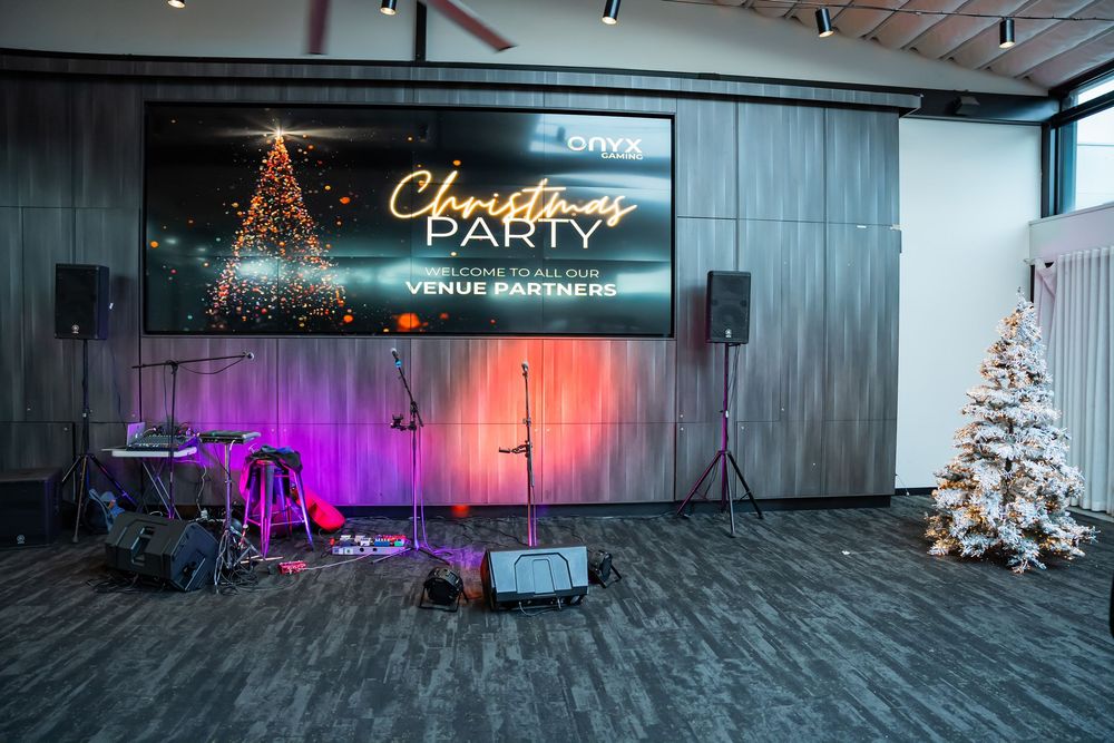An empty event space with illuminated Christmas trees and colored lighting creating a festive holiday atmosphere.