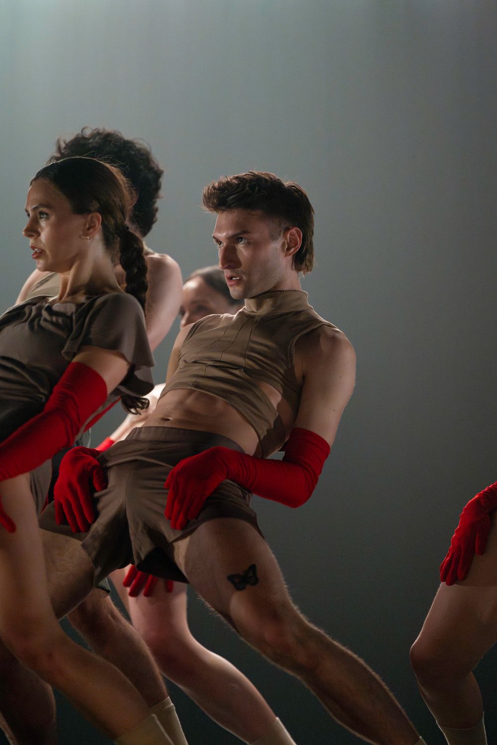 Contemporary dancers perform in brown and red costumes during dramatic stage performance.