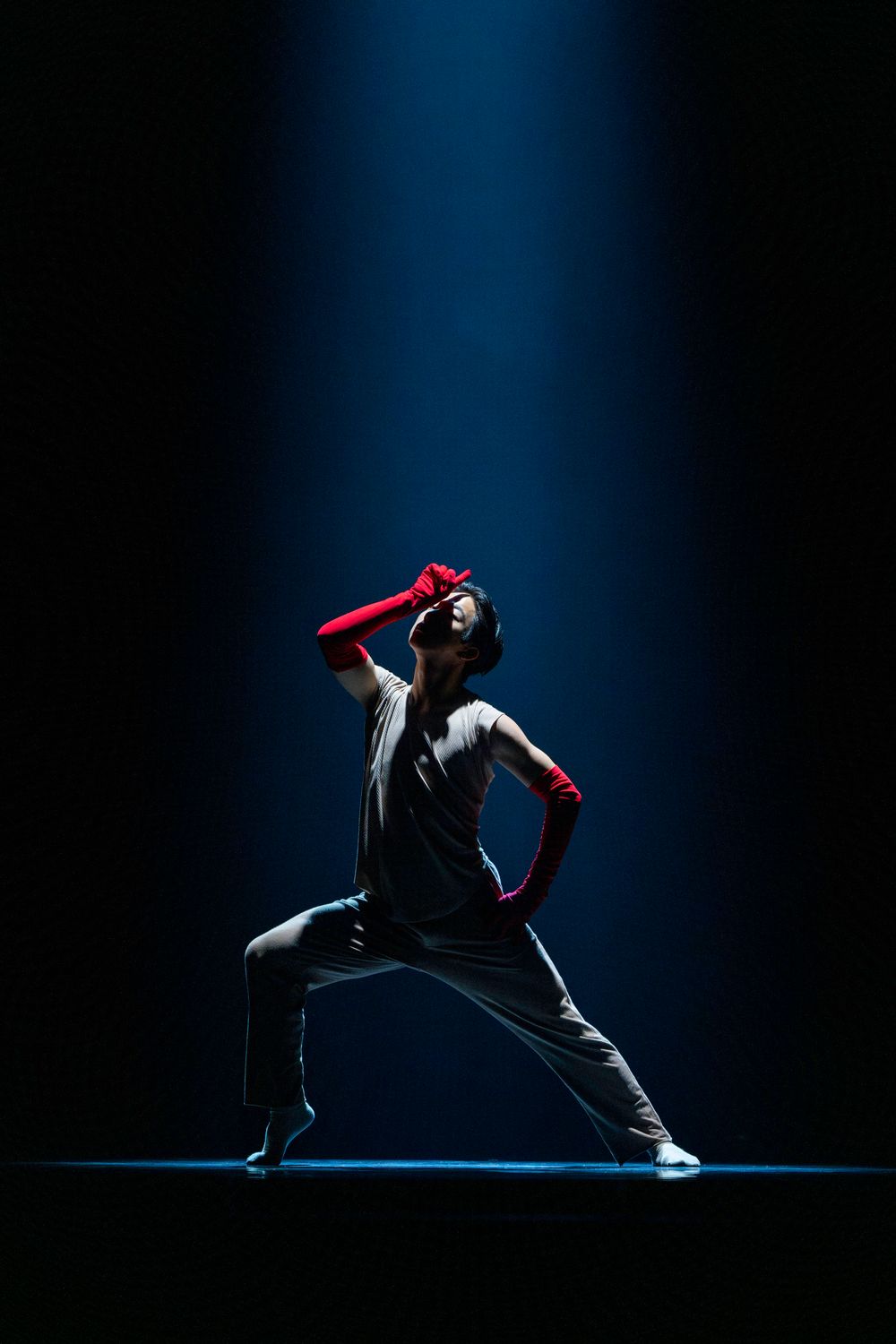 Dramatic dance sequence showing a figure in black against a dark blue backdrop performing dynamic movements.