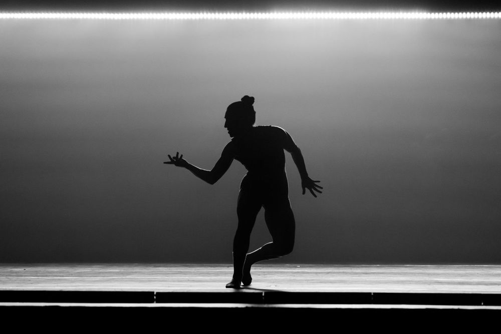 Dramatic silhouette of a figure roller skating in a graceful pose against a stark backlit background.
