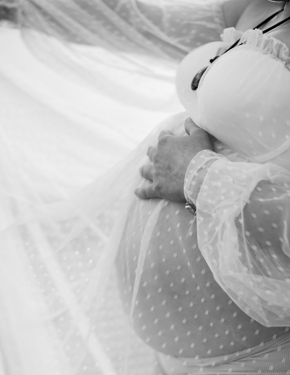 Close up detail of delicate white polka dot tulle fabric with soft draping and translucent layers.