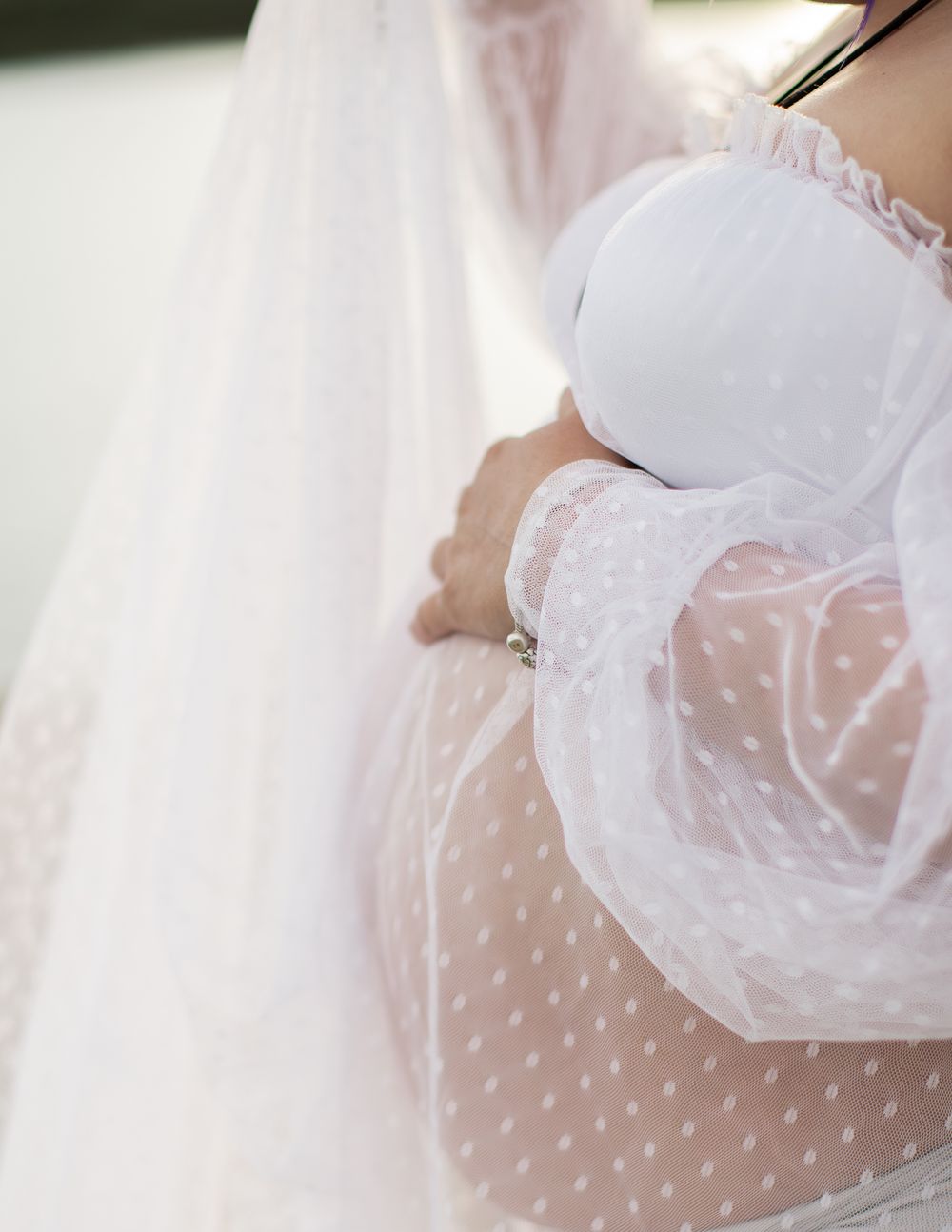 Elegant white polka dot wedding dress with sheer fabric and flowy design details captured in soft lighting.