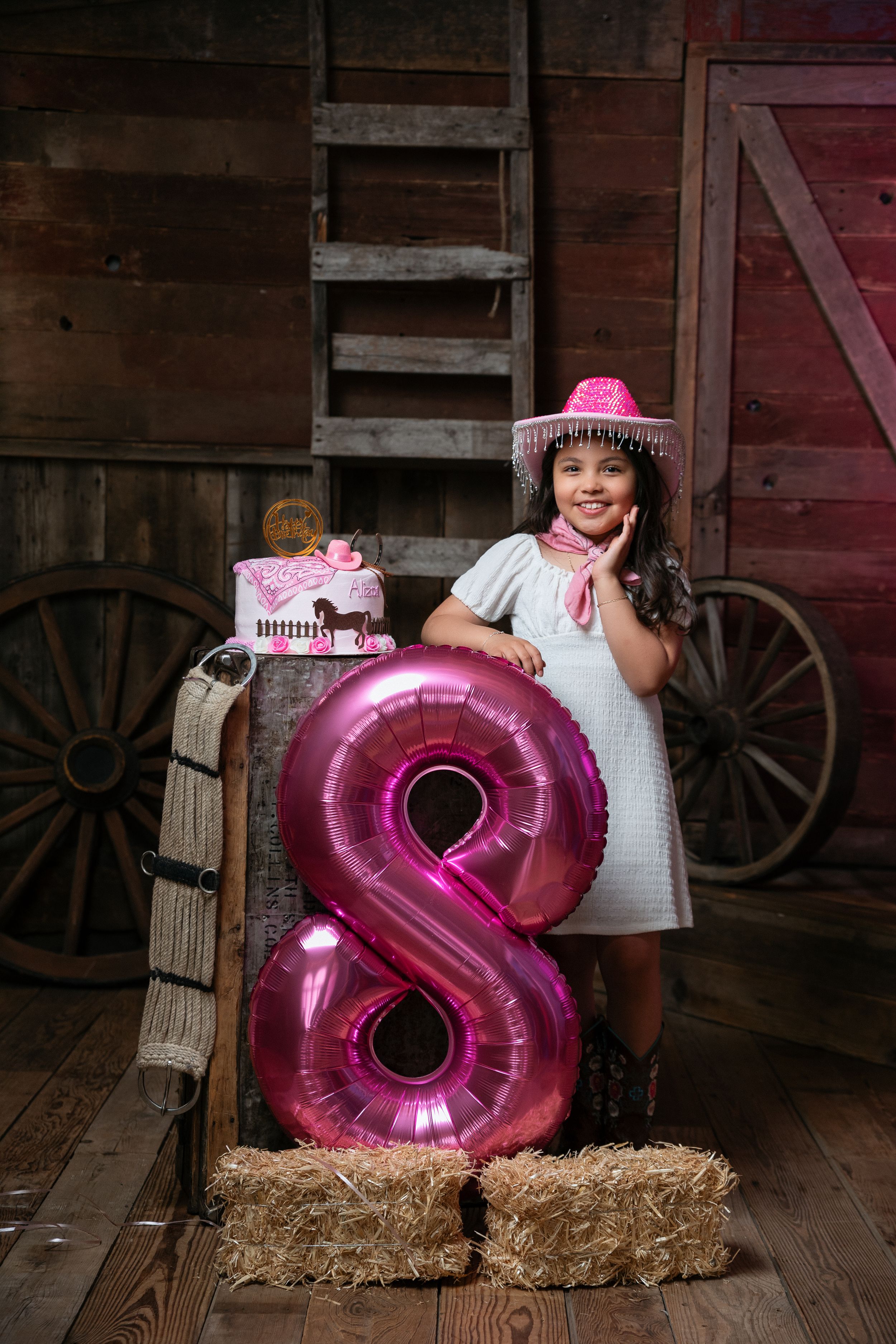Pink number 8 balloon displayed on hay bale for birthday photoshoot.