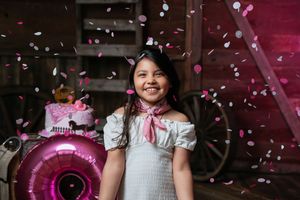 Birthday celebration with pink confetti falling in rustic barn setting.
