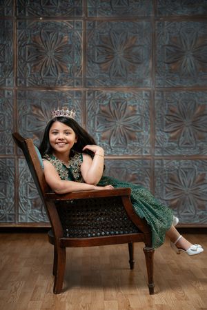 Vintage-style portrait setup with wooden chaise lounge against metallic tile backdrop.
