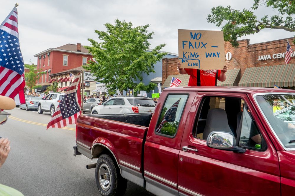 A classic red Ford F250 pickup truck parked at a patriotic event with American flags displayed around it.