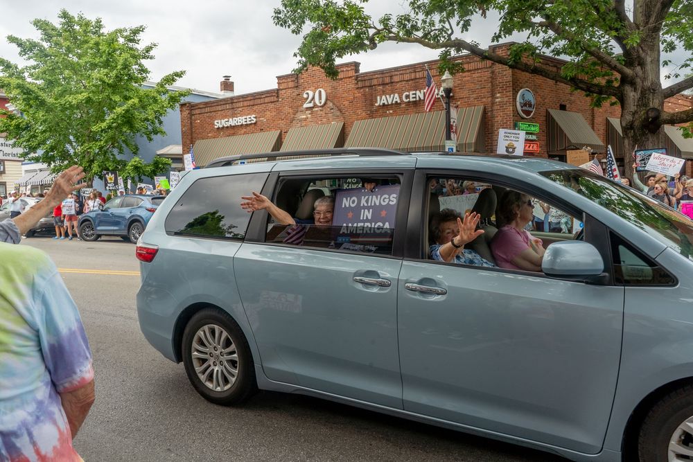 A line of Honda Odyssey minivans at a car dealership with trees in the background.