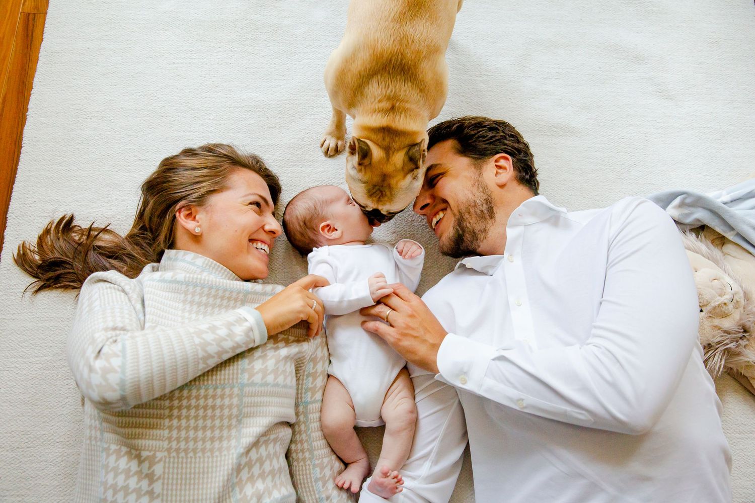 Family lying on floor with dog while cuddling newborn baby.