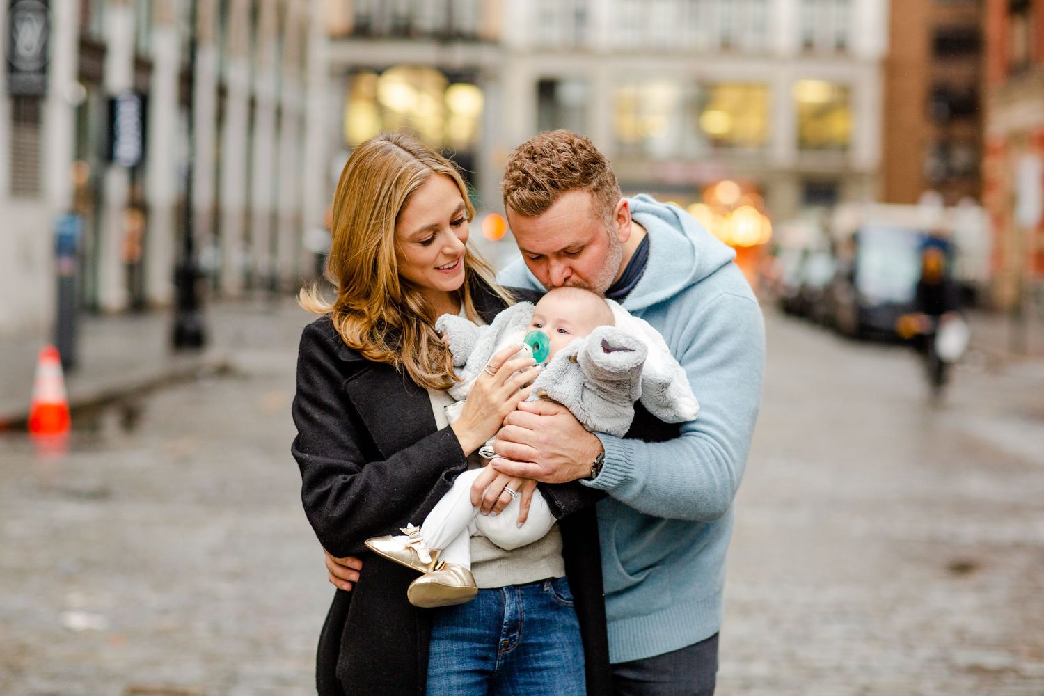 A couple shares an intimate moment with their newborn baby on a city street.