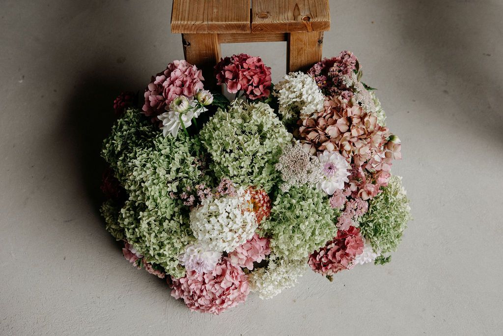 Top view of lush pink and green hydrangea floral arrangement on concrete floor.