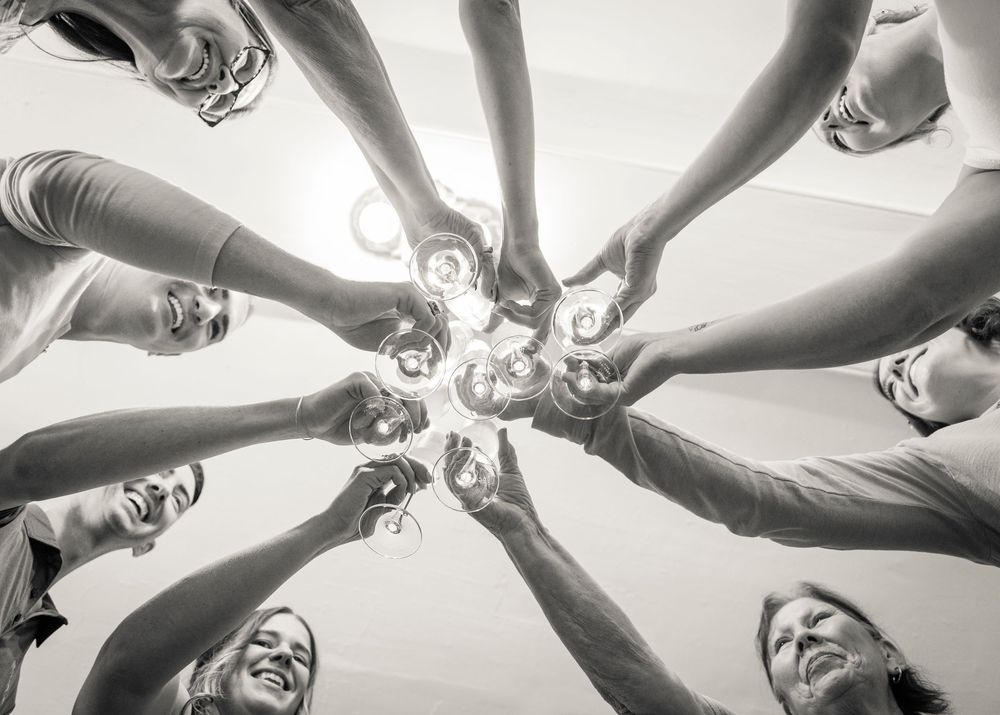 A group forms a circle with their hands joined together viewed from below in black and white.