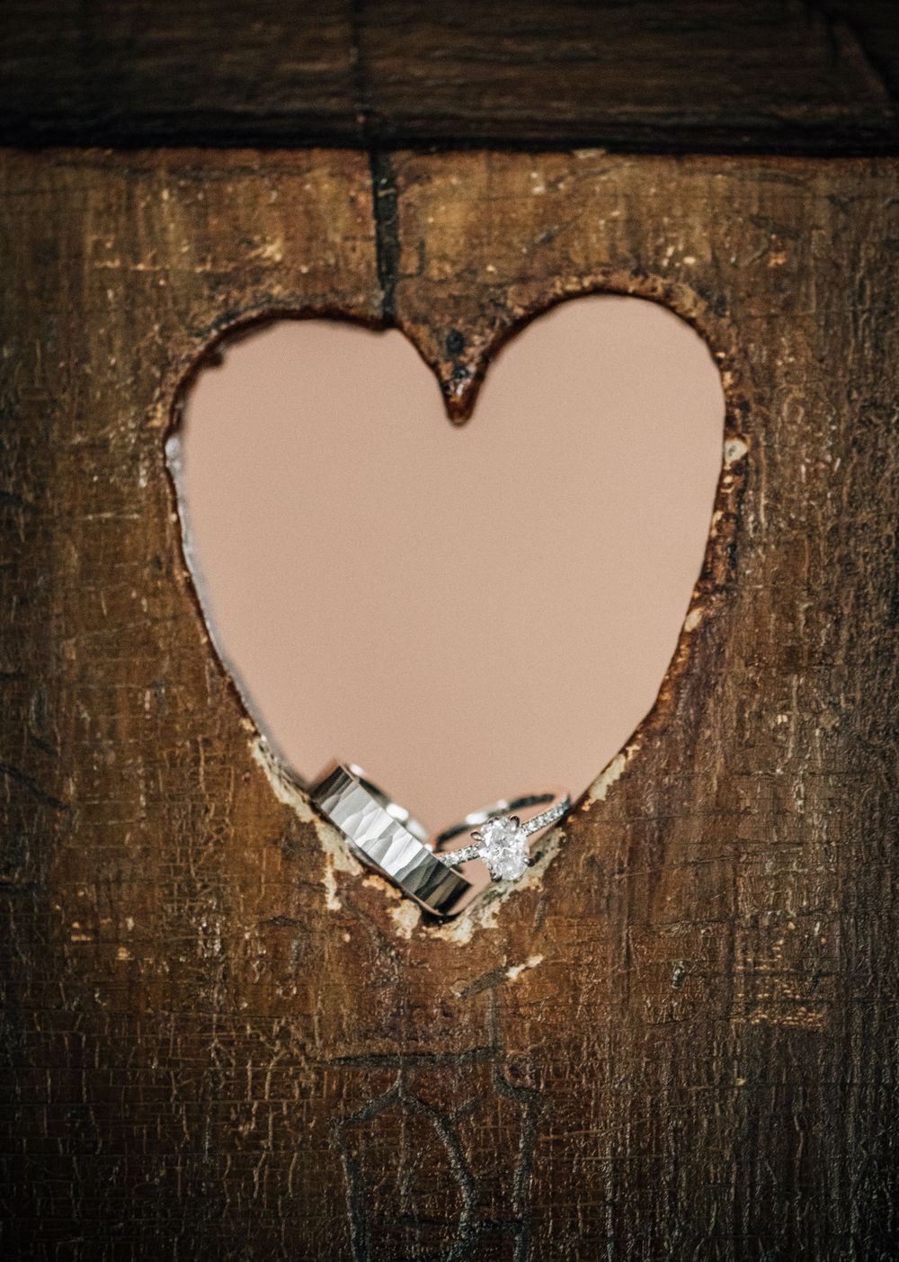 A sequence of heart-shaped cutouts in a rustic wooden surface with a padlock visible through one of the openings.