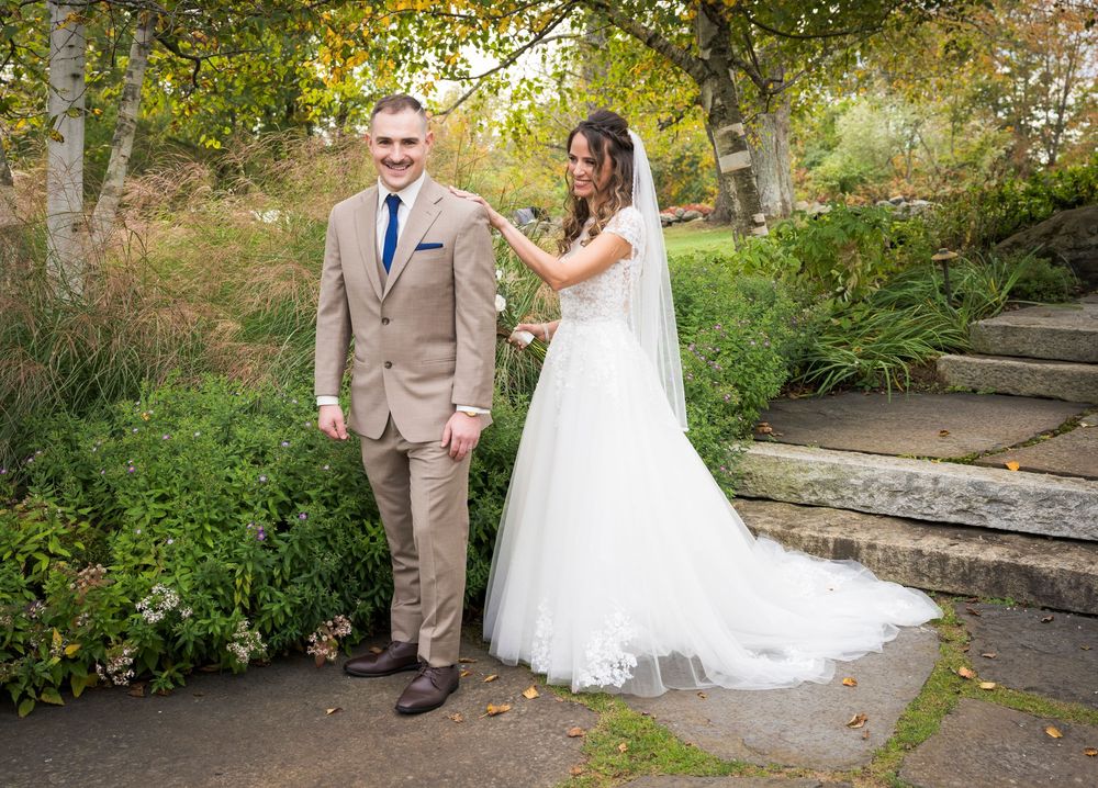 A couple shares a playful moment on stone steps surrounded by autumn foliage.