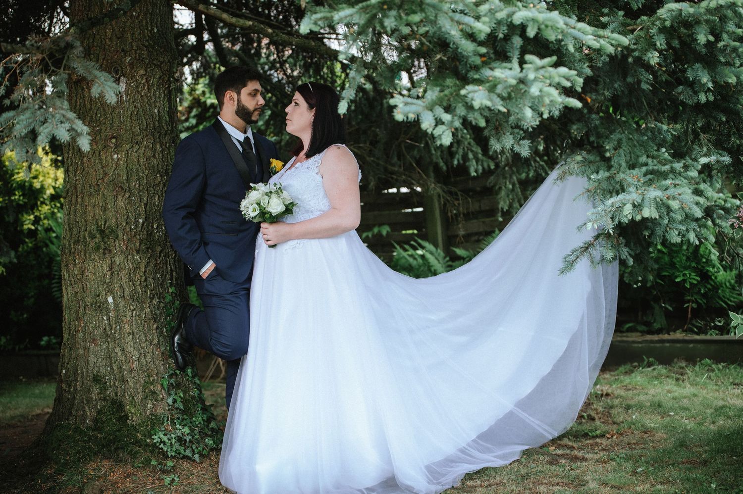 Wedding couple poses under tree branches for romantic outdoor portraits.