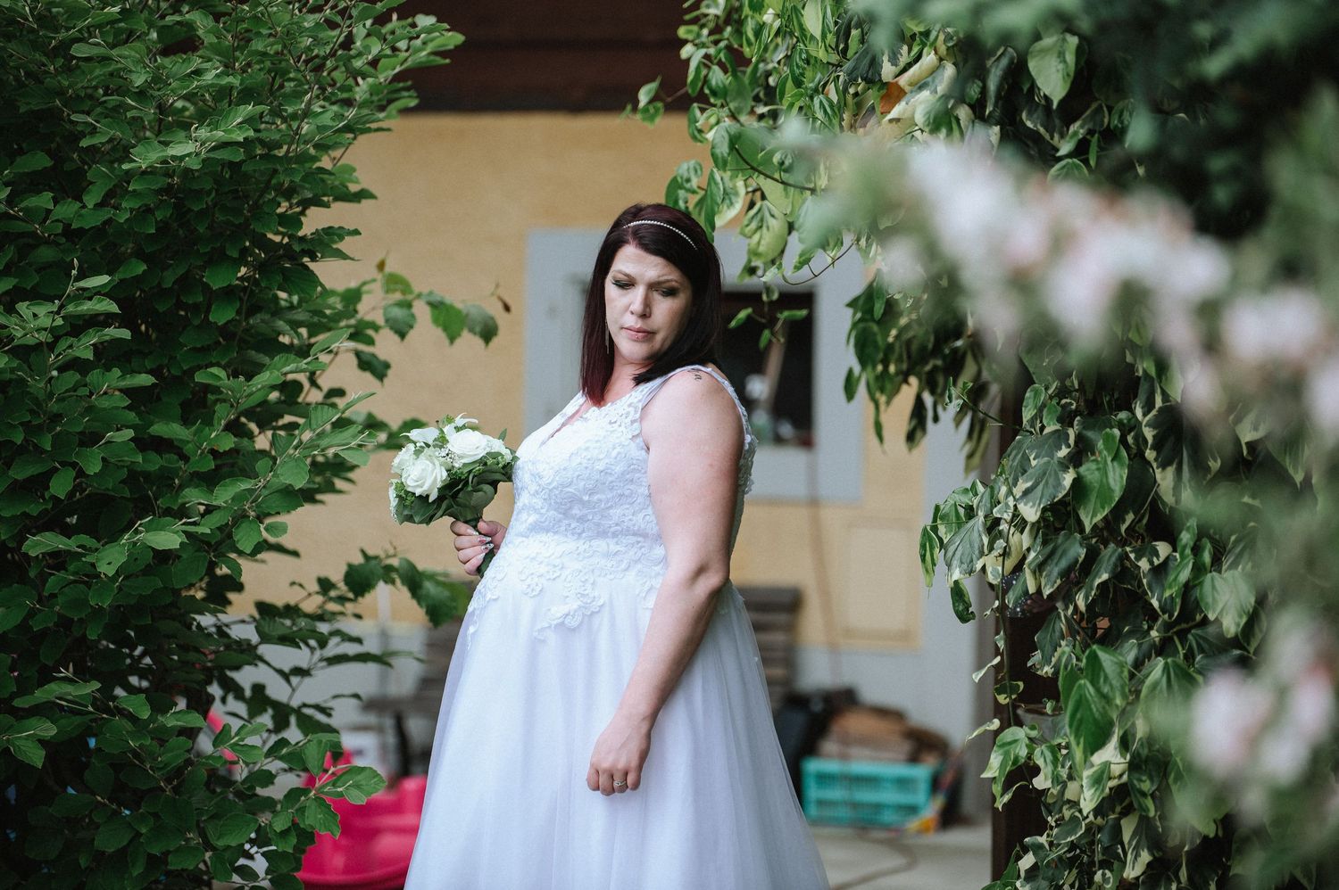 A couple shares intimate wedding photos in a garden setting with flowering trees.
