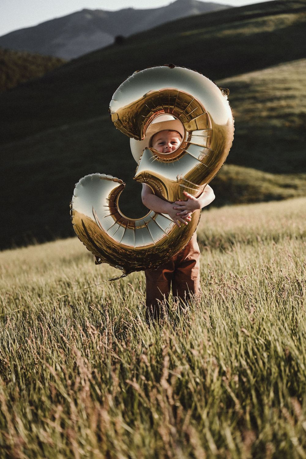 Large inflatable numbers in a golden field with mountains in the background at sunset.