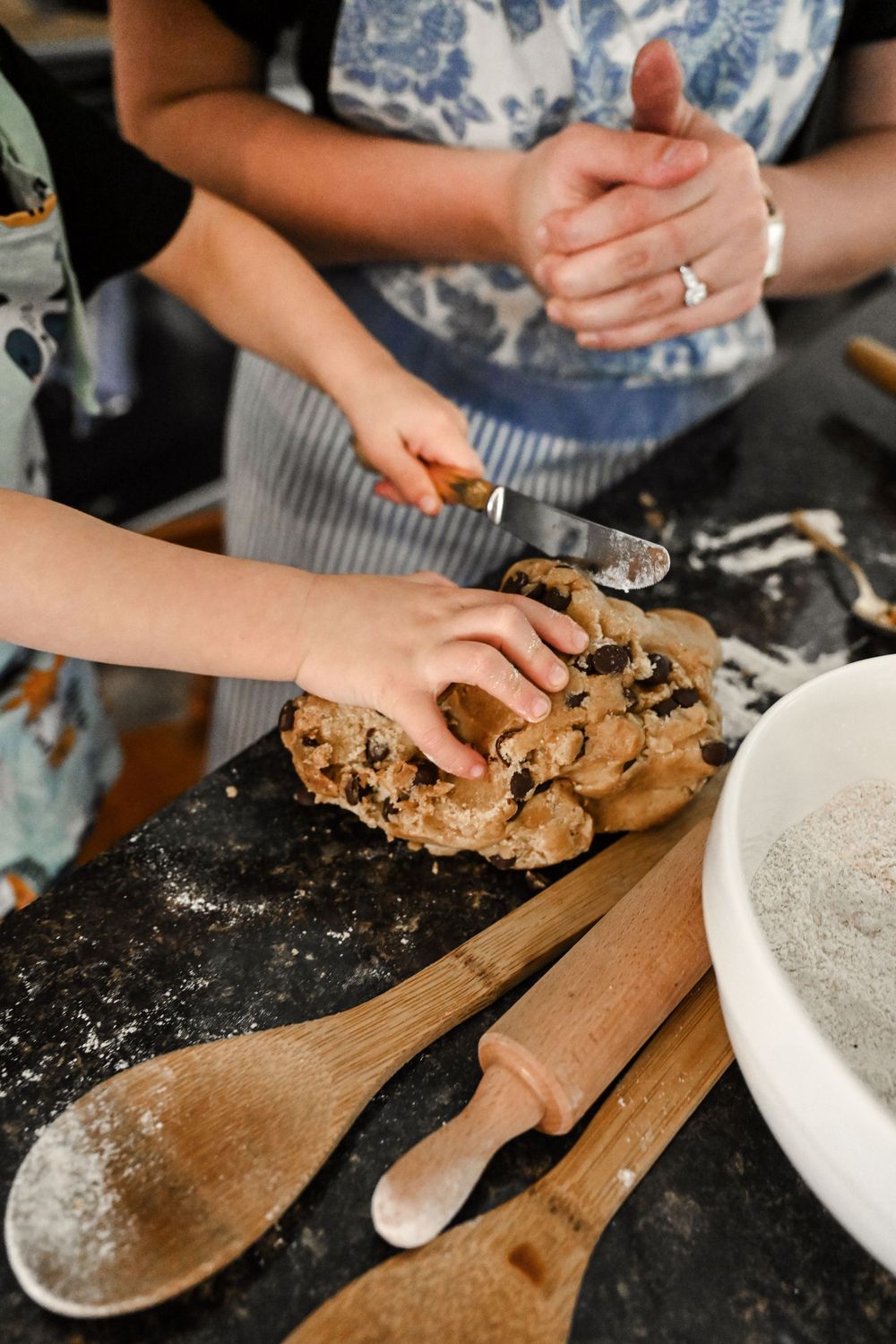 Close-up shots of hands kneading and working with cookie dough on a dark surface.
